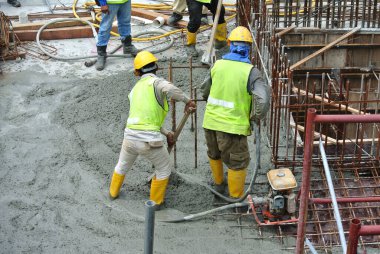 MELAKA, MALAYSIA -NOVEMBER 13, 2015: Construction worker leveling poured wet concrete. They also use a vibrator machine in this work.