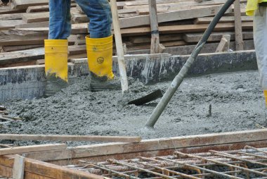 JASIN, MALAYSIA -NOVEMBER 13, 2015: Construction worker leveling poured wet concrete. They also use a vibrator machine in this work.