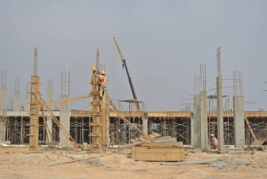 MELAKA, MALAYSIA -JULY 05, 2016: Construction workers wearing safety harness and adequate safety gear while working at high level at the construction site in Melaka, Malaysia.