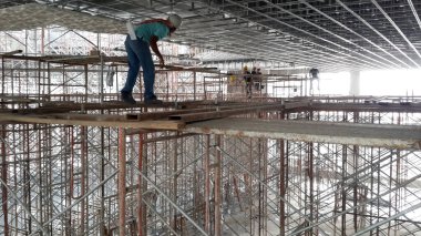 MELAKA, MALAYSIA -JULY 05, 2016: Construction workers wearing safety harness and adequate safety gear while working at high level at the construction site in Melaka, Malaysia.