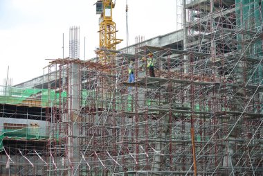 MELAKA, MALAYSIA -JULY 05, 2016: Construction workers wearing safety harness and adequate safety gear while working at high level at the construction site in Melaka, Malaysia.