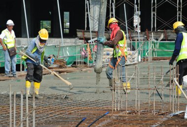 SELANGOR, MALAYSIA -APRIL 16, 2016: Construction workers using a concrete vibrator at the construction site to compact concrete slurry that pour in the form work. 