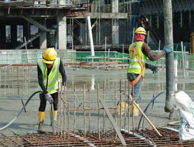 SELANGOR, MALAYSIA -APRIL 16, 2016: Construction workers using a concrete vibrator at the construction site to compact concrete slurry that pour in the form work. 
