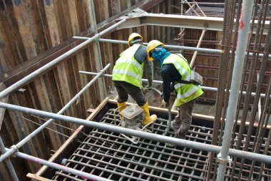 SELANGOR, MALAYSIA -APRIL 16, 2016: Construction workers using a concrete vibrator at the construction site to compact concrete slurry that pour in the form work. 