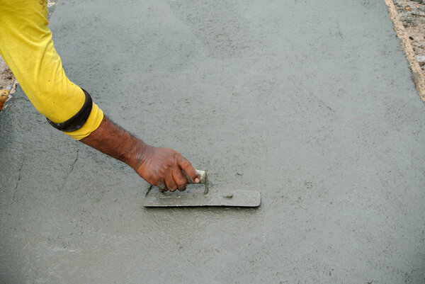 MELAKA, MALAYSIA -FEBRUARY 5, 2016: Close-up of hand using trowel to finish and level wet concrete floor.