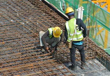 MALACCA, MALAYSIA -27 Mayıs 2016: Malezya 'daki inşaat alanında çelik takviye barı üreten inşaat işçileri. Destek çubuğu ince kabloyla birbirine bağlıydı..  