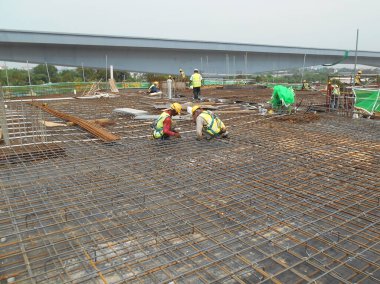 MALACCA, MALAYSIA -MARCH 30, 2016: Construction workers fabricating steel reinforcement bar at the construction site in Malacca, Malaysia. The reinforcement bar was ties together using tiny wire.  