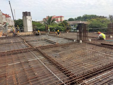 MELAKA, MALAYSIA - 1 Temmuz 2022: İnşaat işçileri yer döşemeleri için çelik takviye çubukları üretiyorlar. Çeşit büyüklükteki inşaat demiri mühendis tarafından dizayn edilip bağlanır..