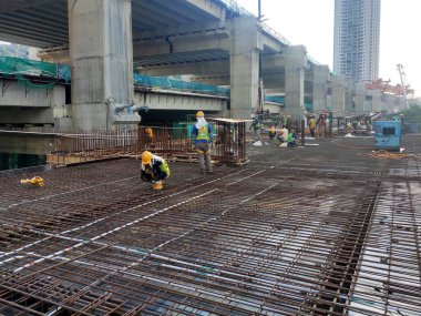 MELAKA, MALAYSIA - 1 Temmuz 2022: İnşaat işçileri yer döşemeleri için çelik takviye çubukları üretiyorlar. Çeşit büyüklükteki inşaat demiri mühendis tarafından dizayn edilip bağlanır..