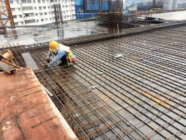 MELAKA, MALAYSIA - 1 Temmuz 2022: İnşaat işçileri yer döşemeleri için çelik takviye çubukları üretiyorlar. Çeşit büyüklükteki inşaat demiri mühendis tarafından dizayn edilip bağlanır..