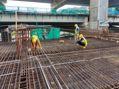 MELAKA, MALAYSIA - 1 Temmuz 2022: İnşaat işçileri yer döşemeleri için çelik takviye çubukları üretiyorlar. Çeşit büyüklükteki inşaat demiri mühendis tarafından dizayn edilip bağlanır..