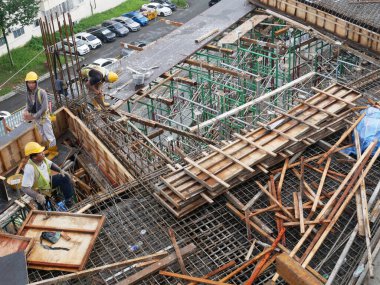 MELAKA, MALAYSIA - 1 Temmuz 2022: İnşaat işçileri yer döşemeleri için çelik takviye çubukları üretiyorlar. Çeşit büyüklükteki inşaat demiri mühendis tarafından dizayn edilip bağlanır..