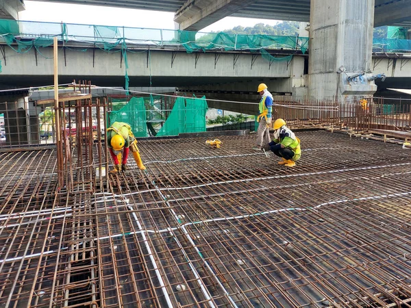 MELAKA, MALAYSIA - 1 Temmuz 2022: İnşaat işçileri yer döşemeleri için çelik takviye çubukları üretiyorlar. Çeşit büyüklükteki inşaat demiri mühendis tarafından dizayn edilip bağlanır..