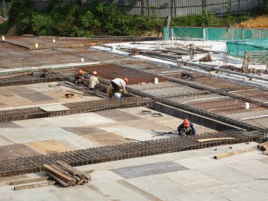 MELAKA, MALAYSIA - 5 Haziran 2022: İnşaat işçileri güvenliklerinden emin olmak için yükseklerde çalışır ve güvenlik teçhizatı giyerler. Gruplar halinde çalışır ve görevlerini yerine getirirler..