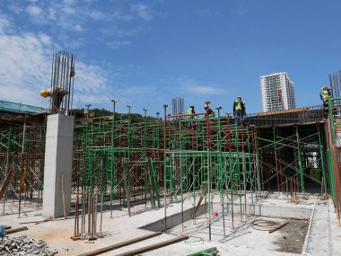 MELAKA, MALAYSIA - 5 Haziran 2022: İnşaat işçileri güvenliklerinden emin olmak için yükseklerde çalışır ve güvenlik teçhizatı giyerler. Gruplar halinde çalışır ve görevlerini yerine getirirler..