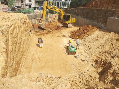 MELAKA, MALAYSIA -5 Nisan 2022: İnşaat işçileri bir inşaat alanında çalışıyorlar. İstenmeyen olayları önlemek için güvenlik önlemi olarak güvenlik giysileri giyiyorlar..