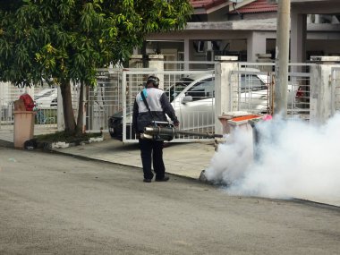 MELAKA, MALAYSIA - 1 Haziran 2022: Sivrisinek savar sisi özel bir makine kullanılarak gerçekleştiriliyor. Sprey işçileri zehrin kokusunu almamak için özel bir maske takmak zorundadırlar..