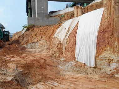 MELAKA, MALAYSIA - 6 Temmuz 2022: Kesilen yamaçlar, yağmur suyunun yol açtığı erozyonu önlemek için bir süreliğine plastik veya kumaş kullanılarak geçici olarak kapatılmıştır. Bu acil bir durum..