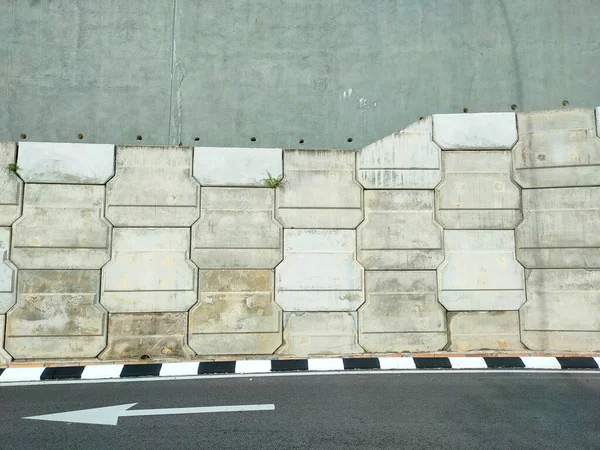 Precast concrete retaining wall panels are installed in layers as a retaining wall. This retaining wall functions to prevent erosion and also as a vertical dividing wall between two levels.