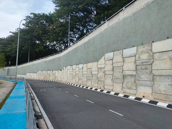 Precast concrete retaining wall panels are installed in layers as a retaining wall. This retaining wall functions to prevent erosion and also as a vertical dividing wall between two levels.