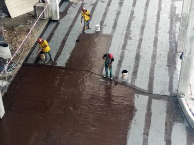 MELAKA, MALAYSIA - 1 Temmuz 2022: İnşaat işçileri tarafından beton levhanın üzerine uygulanan su geçirmez zar. Su geçirmez katman beton levhanın altından suyla geçmesini engellemek için.. 