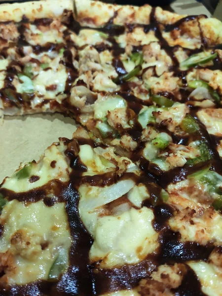 Close-up photo of the pizza slice still in the box. Pizza is made with a variety of toppings as a flavor variation with cheese as the base of the topping ingredients.