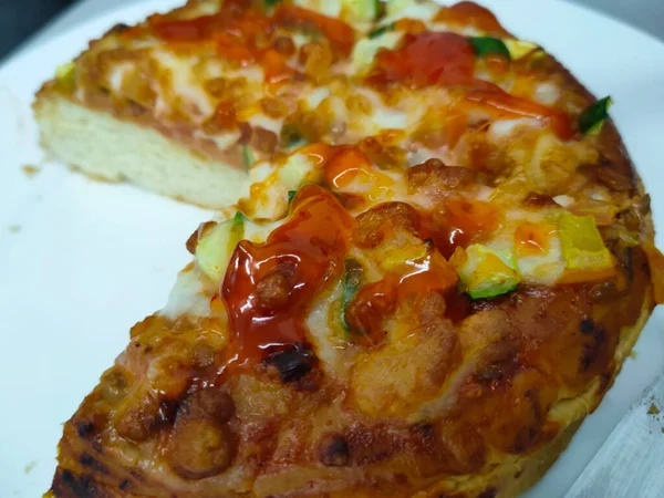 Close-up photo of the pizza slice still in the box. Pizza is made with a variety of toppings as a flavor variation with cheese as the base of the topping ingredients.