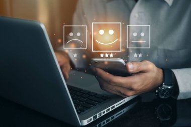 İş adamı, mutlu gülen yüz ikonu ile telefonda sanal ekran kullanarak hizmette tatmin oluyor. Reyting çok etkileyici. Müşteri hizmetleri ve Memnuniyet kavramı