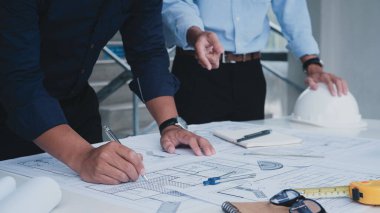 İki Asyalı mühendis inşaat mühendisi. İş yerindeki mühendislik objeleri ile partnerler arka planda etkileşime giriyor. Emlak kavramı