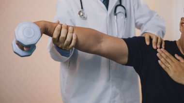 Fizyoterapistler klinikteki hastaların dirseklerini kontrol ediyor. Ellerinin görüntüsünü kapat.