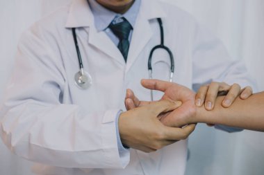 Doktor hastanın el ağrısını kontrol ediyor. Beyaz önlüklü beyaz bir adamın, beyaz önlüklü, kıdemli bir beyaz adamın elini hareket ettirmesi.. 