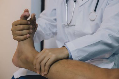 İnsan ayağı üzerinde egzersiz yapan bir fizyoterapistin yakın çekimi. Hasta ayağının sapını acıyı kontrol etmek için kullanıyor.