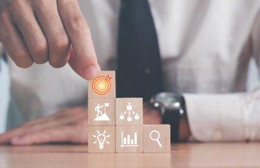 İş geliştirme kavramını hedefliyorum. İş adamı el, ahşap bloğu ikon iş stratejisi ve eylem planı ile düzenliyor.