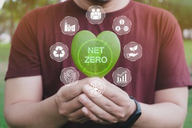 Ağ sıfır ve karbon nötr konsept. Ellerinde yeşil ağ sıfır ikonu ve yeşil ikon olan kalp yaprağı tutan yetişkinler. Net sıfır sera gazı emisyon hedefi. İklim tarafsız uzun vadeli stratejisi. 