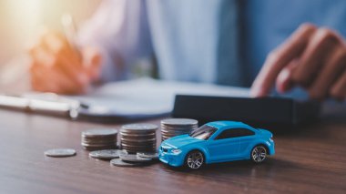 Araba modeli ve parası olan hesap makinesi kullanan, tasarruf ve benzin maliyetlerini sayan alıcı veya satış fiyatı, araç değeri veya yol vergisi hesaplayan pazarlamacı.