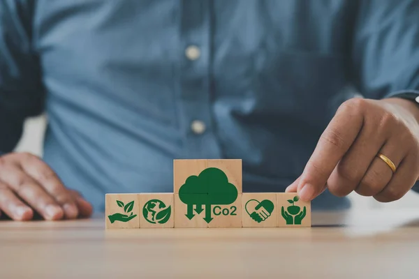 İnsan eli ahşap küplere CO2 emisyon azaltma ikonu koyar. CO2 emisyon konsepti. Green Industries iş konsepti.