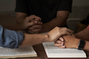 İnanmak için dua eden Hıristiyan bir grup insan ve ibadet ya da ibadet kavramı için ahşap bir masada İncil.