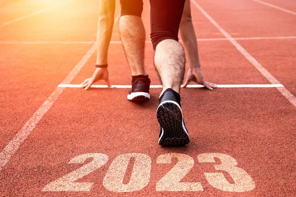 Goals and plans for the next year. Rear view of a man preparing to start on an athletics track engraved with the year 2023