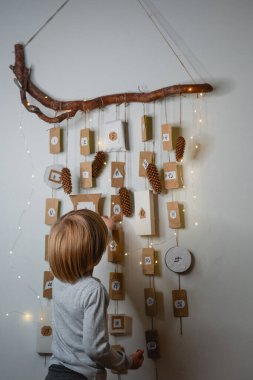 Takvimin yanında duran küçük çocuk. Noel için bekleme kavramı.