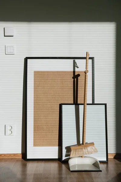 Vassoura e colher kit de pé na frente de molduras em appartment. Equipamento de limpeza residencial de madeira elegante. — Fotografia de Stock