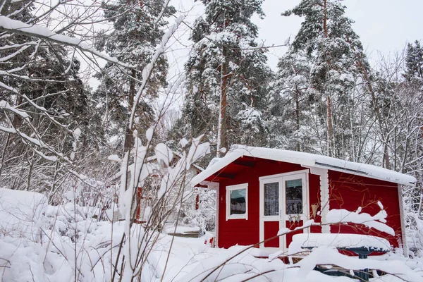 Rood houten afwerking huis in de winter bedekt met sneeuw. — Stockfoto