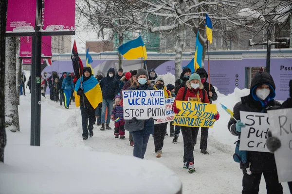 Protestante andando com cartazes em prostesto contra a agressão russa. Helsínquia, Finlândia, 7.02.2022 — Fotografia de Stock Grátis