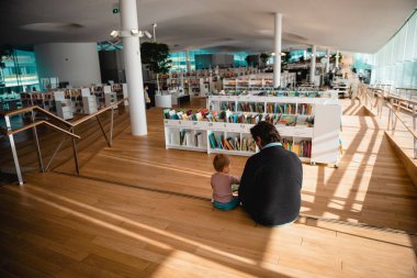 FINLAND, HELSINKI - 17 Haziran 2021 Helsinki Merkez Kütüphanesi Oodi. Baba çocuğa kitap okuyor..