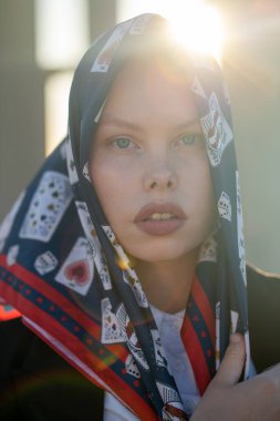 Kusursuz kusur. Beyaz kavisli model ipek bir başörtüsü takıyor. Arka planda güneş ışığı. Doğal güzellik..