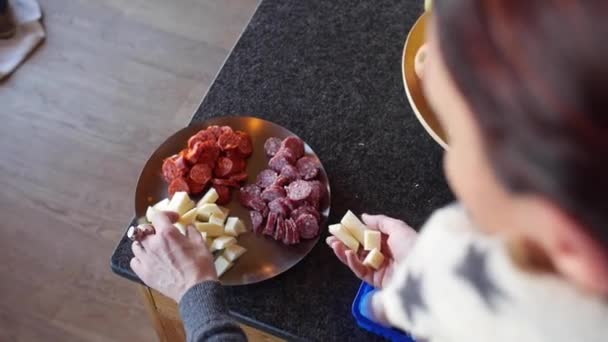 Руки женщины готовят тапас на тарелке с сыром и сосисками. — стоковое видео