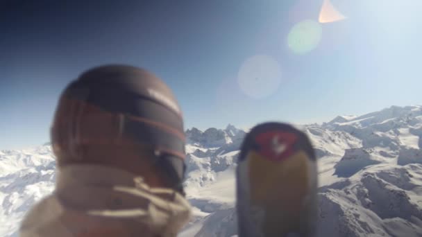 Arkadan kayakçı arka planda karlı dağların destansı manzarasıyla. Mercekte güneş parlıyor. — Stok video