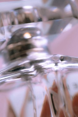 Makro yakın plan bir parfüm şişesi Pastel renkli mavi ve pembe ışık. Kristal yansımaları. Kadınsı arkaplan.