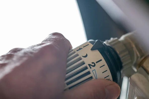 Close-up van de hand draaien thermostaat naar beneden. Zet de verwarming uit. Gasprijs. Besparingen. — Stockfoto