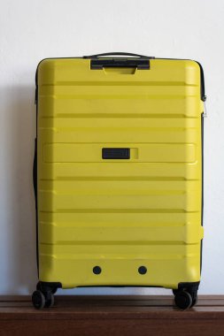 Sarı bavul beyaz bir duvara yaslanmış.. 