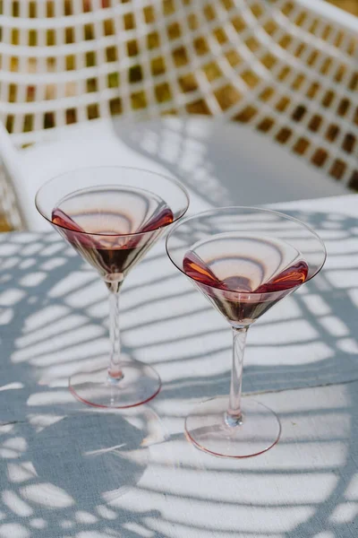 Two glasses with cold pink rose on a garden table in the summer sun. High quality photo